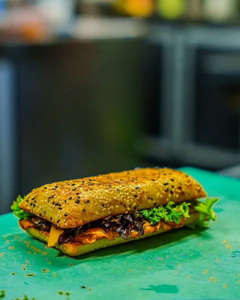 Chef plating a sandwich with fresh greens